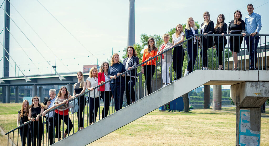 Das Team von HCPM auf einer Treppe vor der Kulisse der Stadt Düsseldorf